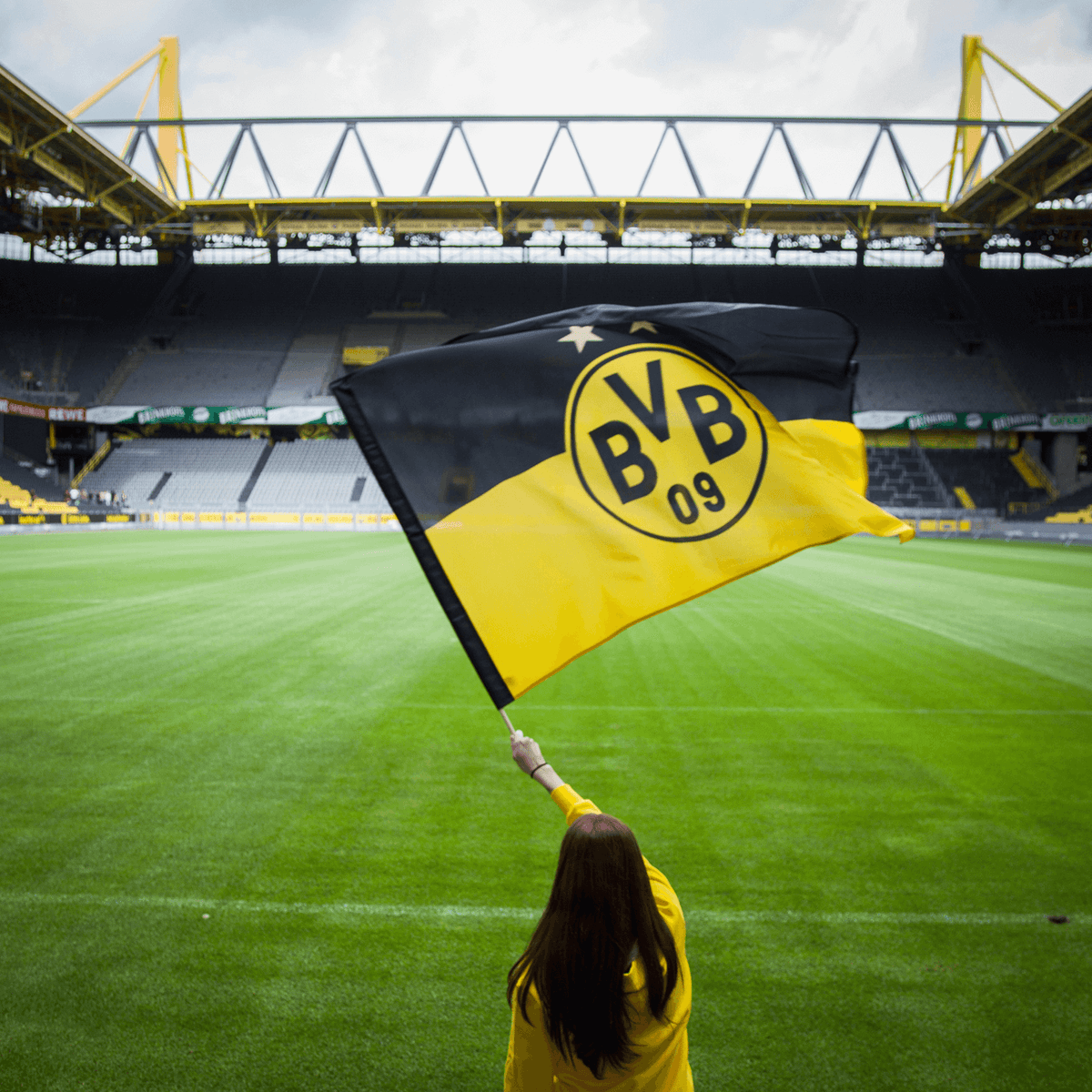 Bandera del BVB en negro y amarillo con el logotipo «BVB-09», que luce una persona en el SIGNAL IDUNA PARK, ideal para los aficionados al fútbol y los seguidores del Borussia Dortmund.
