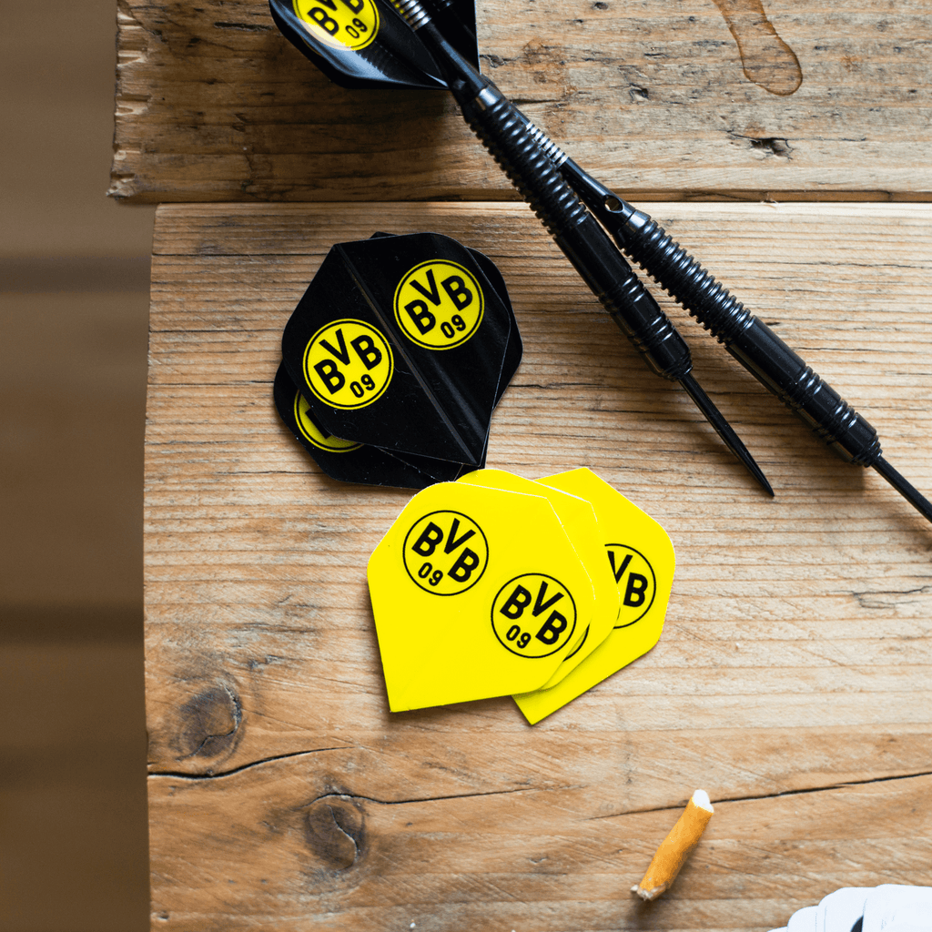 Black-and-yellow BVB dart flights featuring the BVB 09 logo, displayed on a wooden table with darts—the perfect accessory for Borussia Dortmund fans