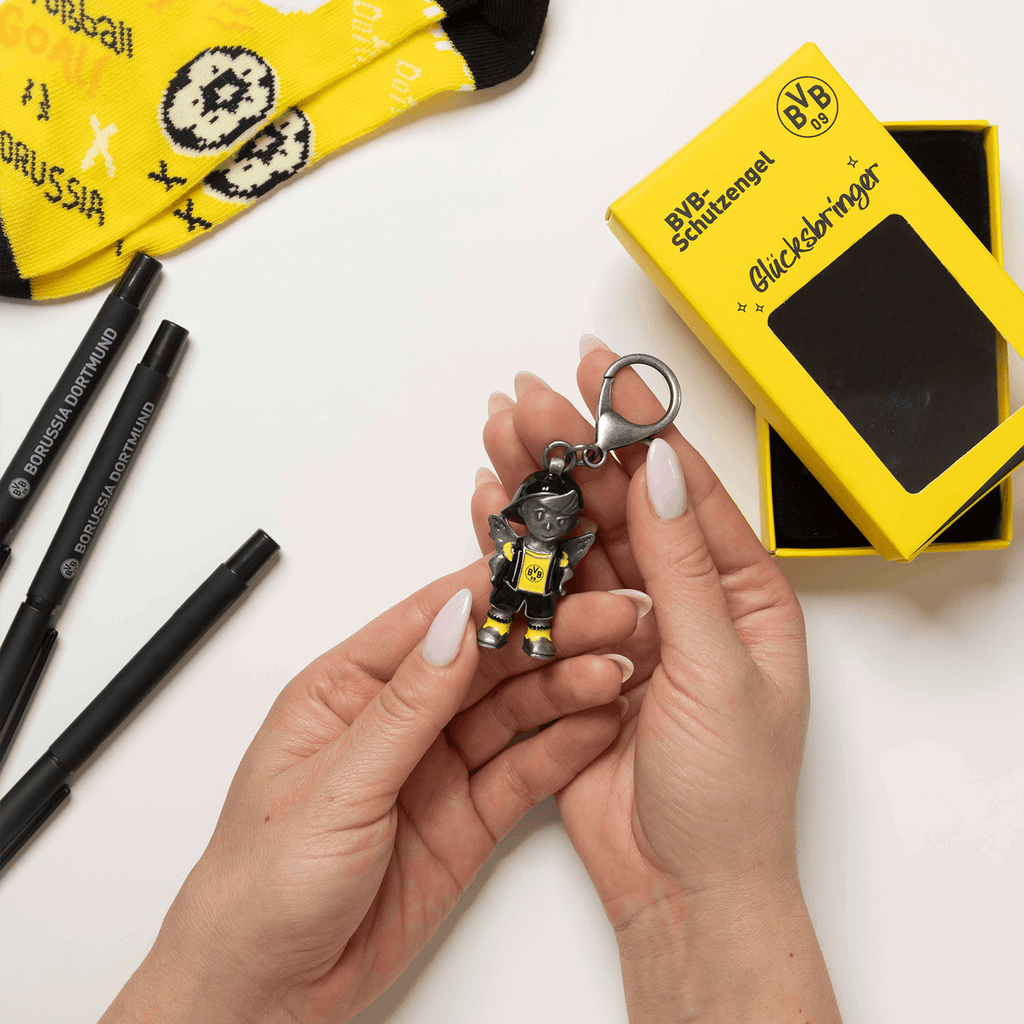 Porte-clés du BVB en forme d'ange gardien, noir et jaune avec l'emblème du BVB, livré dans un emballage cadeau jaune, idéal comme porte-bonheur pour les supporters.