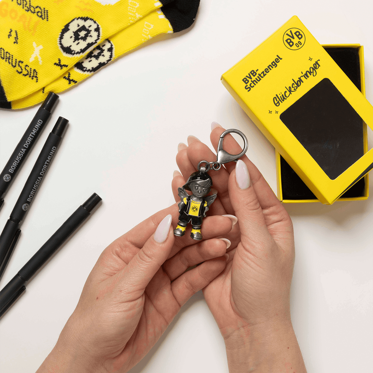 Porte-clés du BVB en forme d'ange gardien, noir et jaune avec l'emblème du BVB, livré dans un emballage cadeau jaune, idéal comme porte-bonheur pour les supporters.