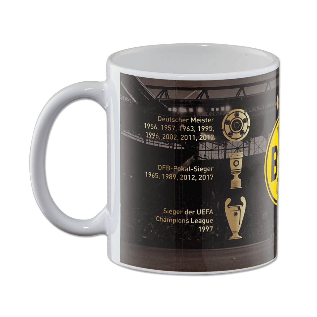 Schwarzgelbe BVB-Tasse mit Borussia Dortmund-Logo und einer Übersicht der Vereins-Erfolge wie Meistertitel, Pokalsiege und Champions-League-Erfolg vor einem Stadionmotiv.