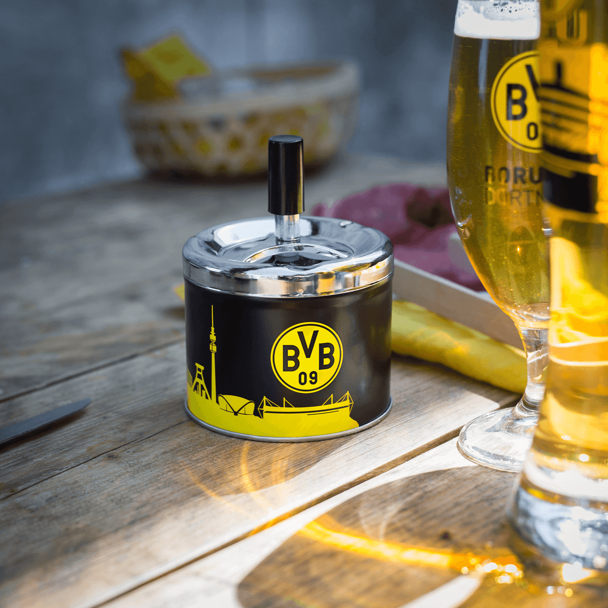 Cendrier rond du BVB avec couvercle, aux couleurs noir et jaune. Orné de l'emblème du BVB et de la silhouette de Dortmund. L'accessoire idéal pour les supporters du Borussia Dortmund.
