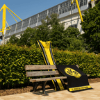Asciugamano nero e giallo del BVB con il grande logo della società e la scritta "Borussia Dortmund", fotografato davanti al SIGNAL IDUNA PARK.