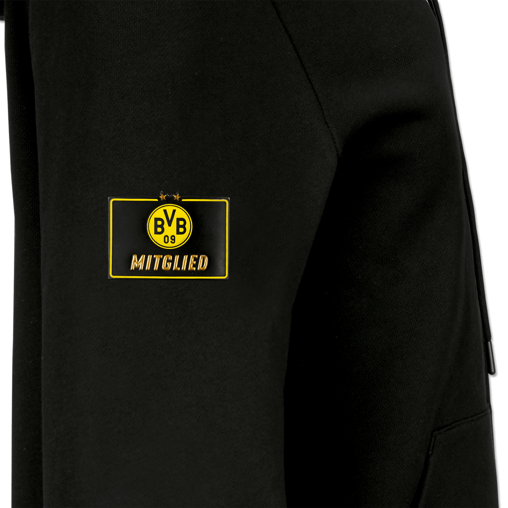 Gros plan sur un sweat à capuche noir du BVB réservé aux membres, orné du logo jaune « BVB-09 » et de l'inscription « Membre » en doré sur la manche.