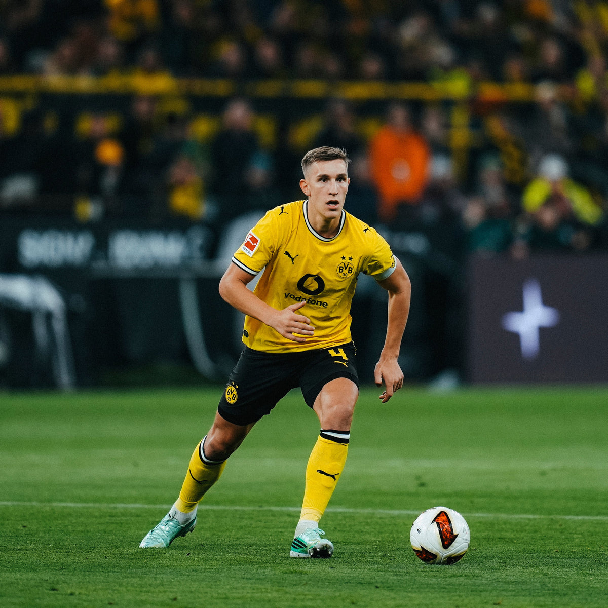 Zu sehen ist der BVB Spieler mit der Nummer 4 - Nico Schlotterbeck. Er ist gerade am Ball und trägt das Authentic Heimtrikot der Saison 26/27.