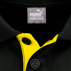 Detailaufnahme eines schwarzgelben Borussia Dortmund Poloshirts mit Puma-Logo und Knopfkragen.