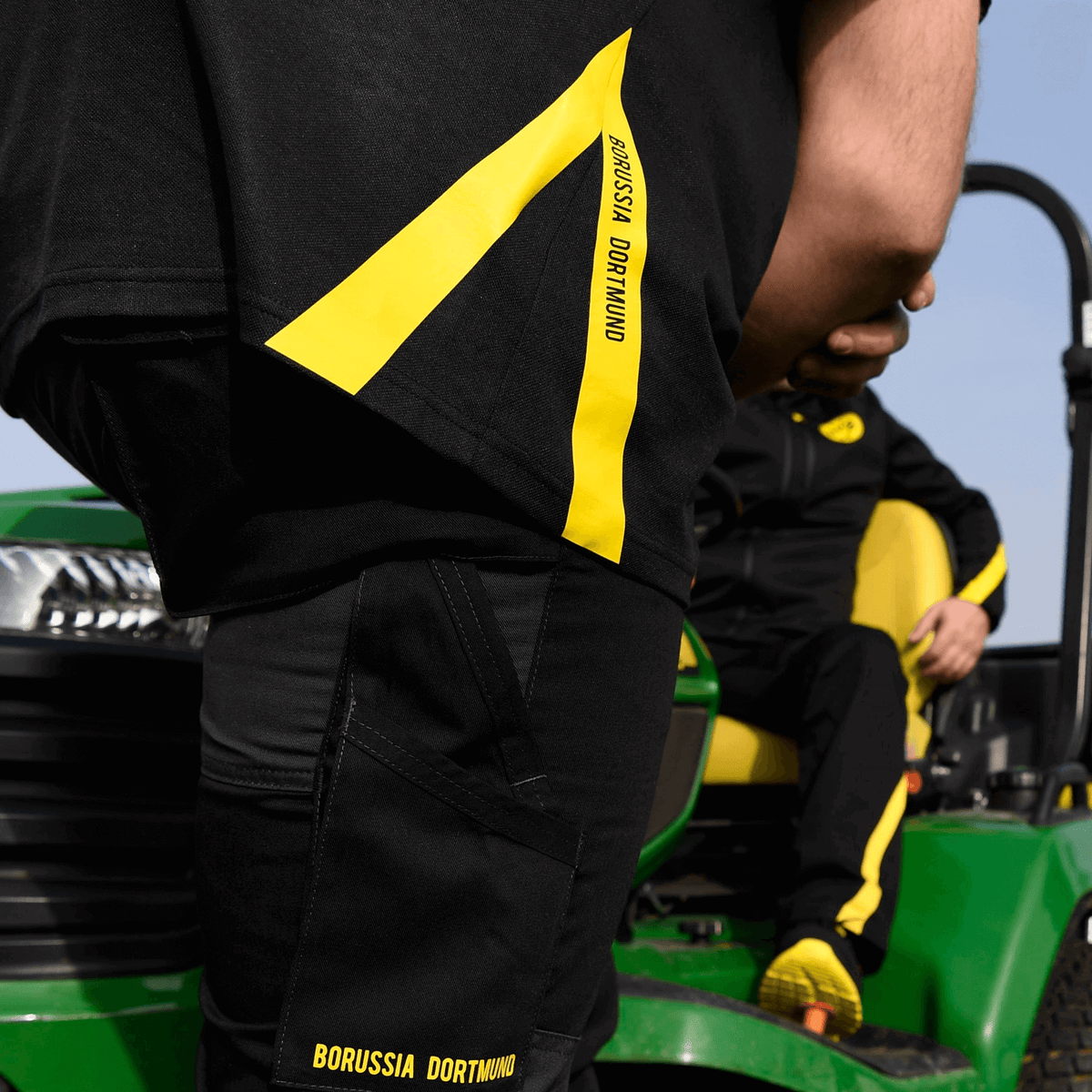Schwarzgelbes Borussia Dortmund Work-Poloshirt mit auffälligen gelben Streifen und BVB-Logo, ideal für Fans.