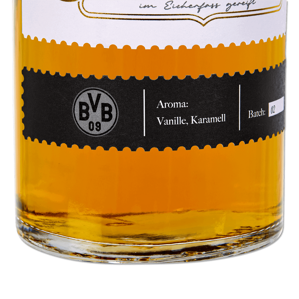 Primer plano de una botella de whisky BVB Bourbon, de color amarillo dorado, con una elegante etiqueta negra, aromas a vainilla y caramelo, y el número de lote 02.