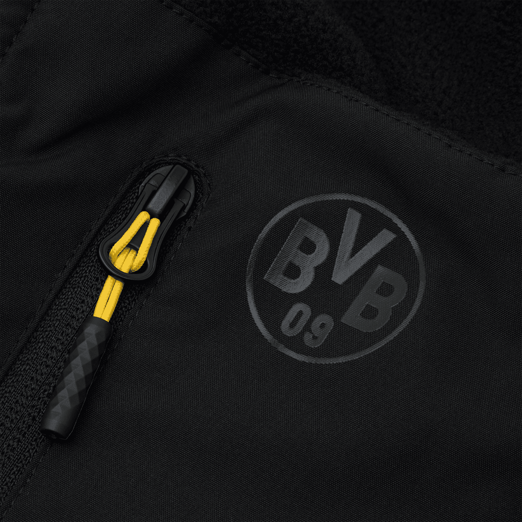 Vue détaillée de la veste polaire noire du BVB, dotée d'une fermeture éclair jaune et du logo du BVB, idéale pour les supporters du Borussia Dortmund.