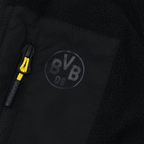 黄色のアクセントとBVB 09ロゴが入った、子供用ブラックのBVBフリースジャケット。ジッパーのクローズアップ写真。