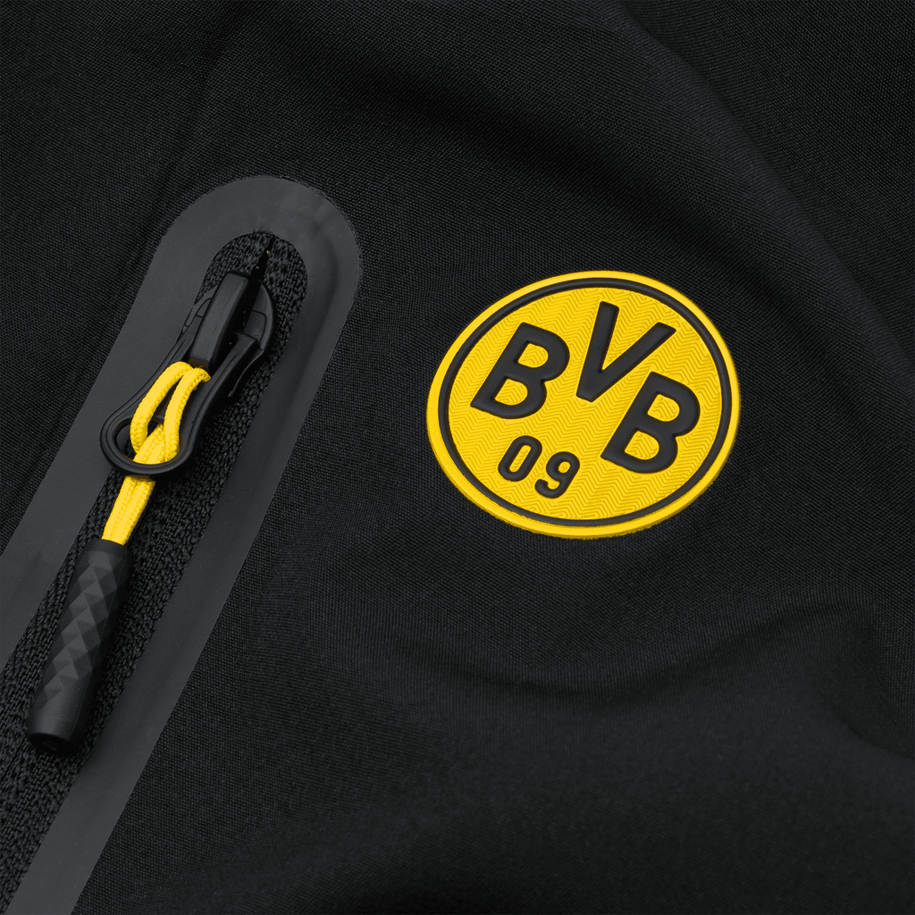Detailansicht der schwarzgelben BVB-Softshelljacke mit auffälligem BVB-Emblem und funktionalem gelbem Reißverschlusszug.