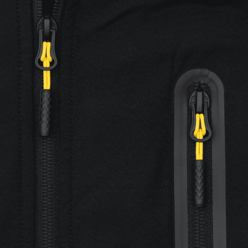 Nahaufnahme der BVB-Softshelljacke in schwarz mit gelben Elementen und Reißverschlüssen, ideal für Outdoor-Aktivitäten und Fans von Borussia Dortmund.