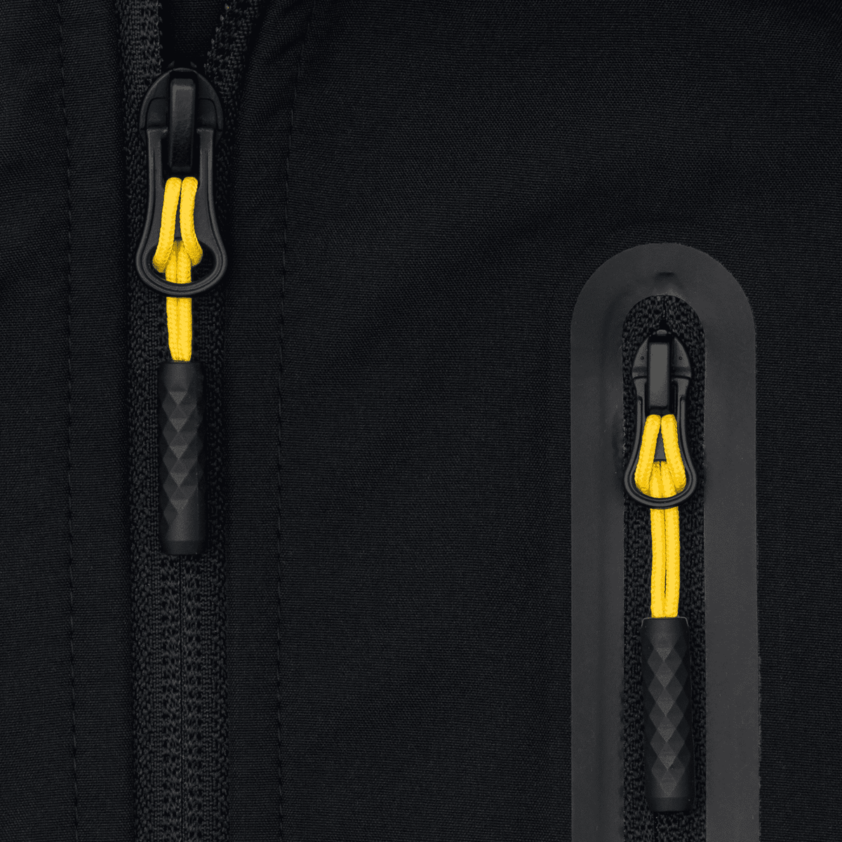 Detailaufnahme einer BVB-Softshelljacke für Kinder in schwarzgelb mit sichtbaren Reißverschlüssen und gelbem Zugband.