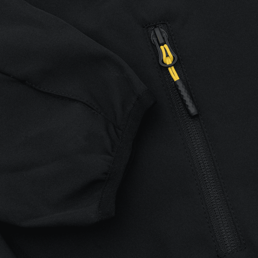 Imagen detallada de una chaqueta softshell negra del BVB para mujer, con cremallera amarilla y mangas a la vista.