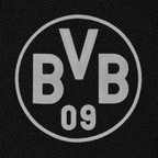 Das Bild zeigt eine Nahaufnahme eines schwarzen BVB-Poloshirts mit großem weißen BVB-Logo auf der Vorderseite.