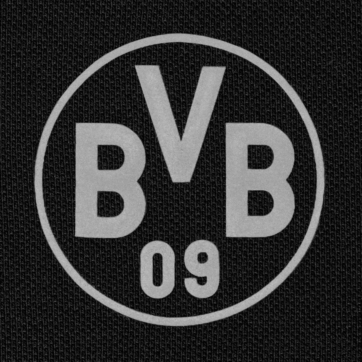 Das Bild zeigt eine Nahaufnahme eines schwarzen BVB-Poloshirts mit großem weißen BVB-Logo auf der Vorderseite.