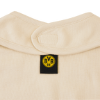 Primo piano di un bavaglino beige del BVB con etichetta nera, logo giallo del BVB e chiusura in velcro.