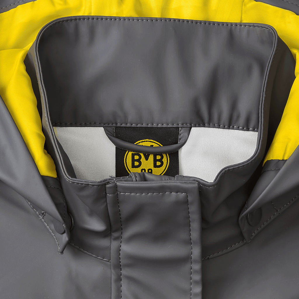 Immagine dettagliata della giacca impermeabile del BVB per neonati e bambini piccoli, di colore grigio con dettagli gialli e logo del BVB.