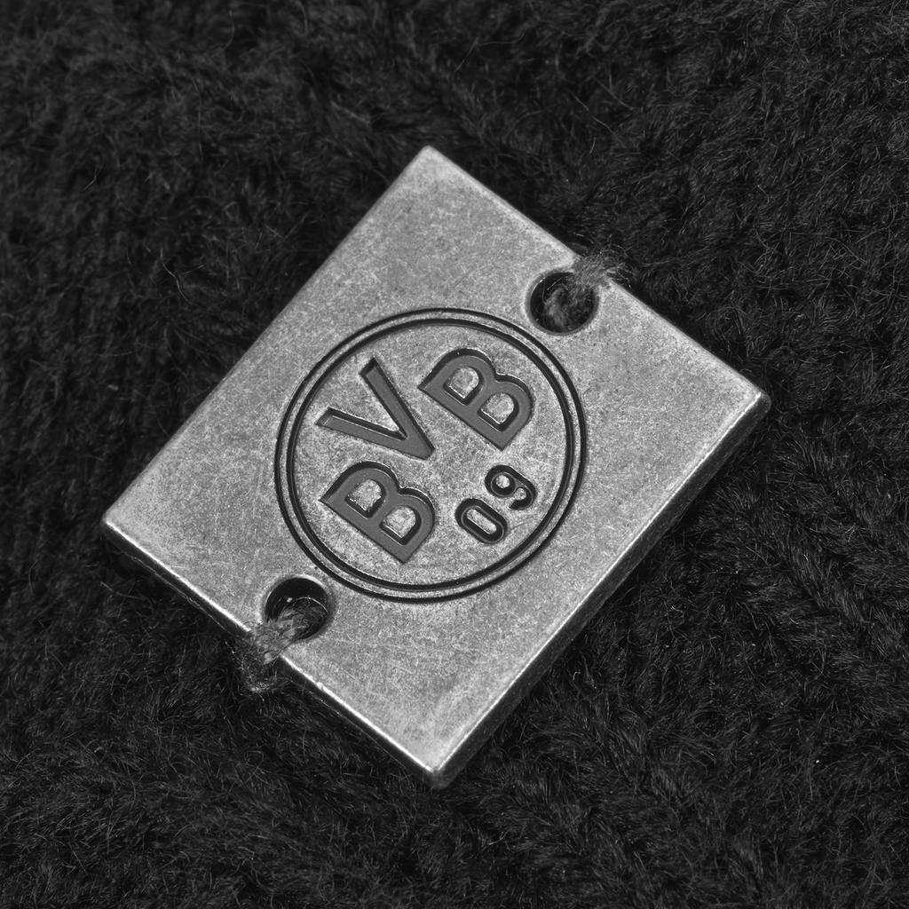 Detailaufnahme einer BVB 09 Bommelmütze für Damen in Schwarz mit einem Metall-Logo und eingeprägtem BVB 09 Schriftzug.