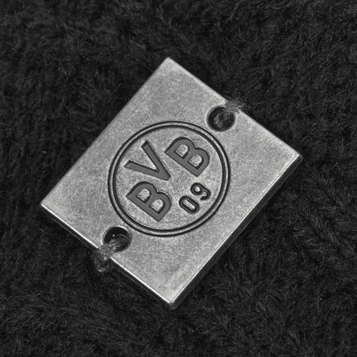 Detailaufnahme einer BVB 09 Bommelmütze für Damen in Schwarz mit einem Metall-Logo und eingeprägtem BVB 09 Schriftzug.