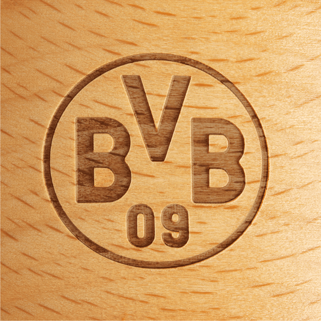 Rundes BVB-Logo als Gravur auf einer Holzfläche, Nahaufnahme mit sichtbarer Maserung des Holzes.