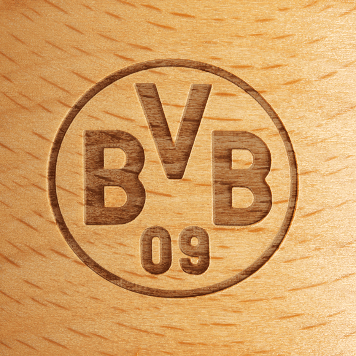 Rundes BVB-Logo als Gravur auf einer Holzfläche, Nahaufnahme mit sichtbarer Maserung des Holzes.