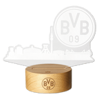 Lampe LED du BVB ornée d'une silhouette stylisée de la ville de Dortmund et d'un grand emblème « BVB 09 » posée sur un élégant socle en bois, idéale comme objet de collection pour les supporters ou comme cadeau.