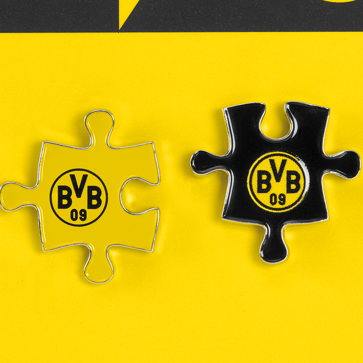 BVB Pin-Set bestehend aus zwei Puzzleteilen in schwarzgelbem Design mit BVB 09 Logo, ideal für Fans und Sammler.