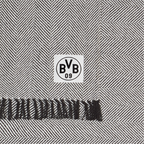Couverture en coton noir et blanc du Borussia Dortmund, motif en chevrons, dimensions 150 x 200 cm, avec le logo du BVB et des franges noires, certifiée GOTS.