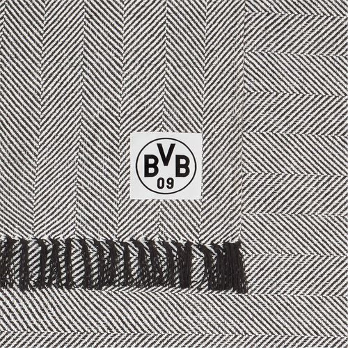 Schwarz-weiße Baumwolldecke von Borussia Dortmund in Herringbone-Muster, 150 x 200 cm groß, mit BVB-Logo und schwarzen Fransen, GOTS-zertifiziert.