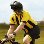 Pantaloncini da ciclismo del BVB nei colori nero e giallo con la scritta “Dortmund” sulla gamba, presentati da un ciclista con casco e occhiali da sole in una scena all’aperto.