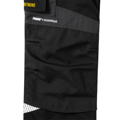 Nahaufnahme der schwarzgrauen BVB Arbeitsbundhose 23/24 mit PUMA-Logo und Workwear-Aufschrift, Teil der aktuellen Borussia Dortmund Kollektion.