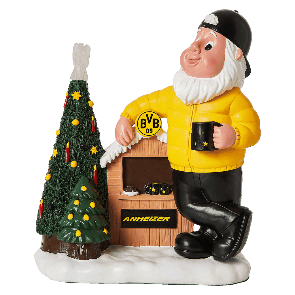 Enano de jardín del BVB con un conjunto amarillo, gorro negro y taza, junto a un árbol de Navidad decorado y una cabaña con el logotipo del BVB y la inscripción «Anheizer».
