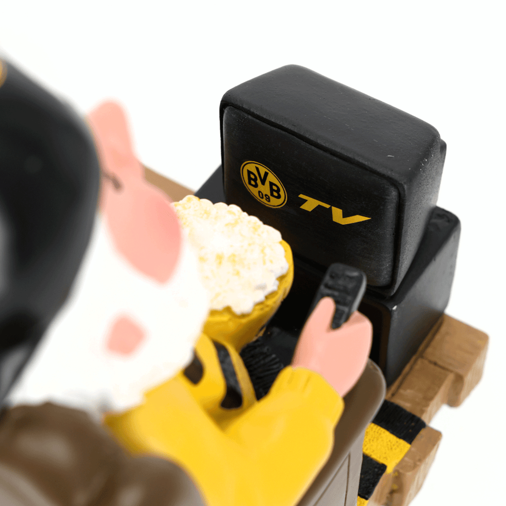 Nano da giardino del BVB nero e giallo con telecomando e popcorn davanti a un televisore con il logo del BVB e la scritta “TV”, ideale come gadget per tifosi e come decorazione.