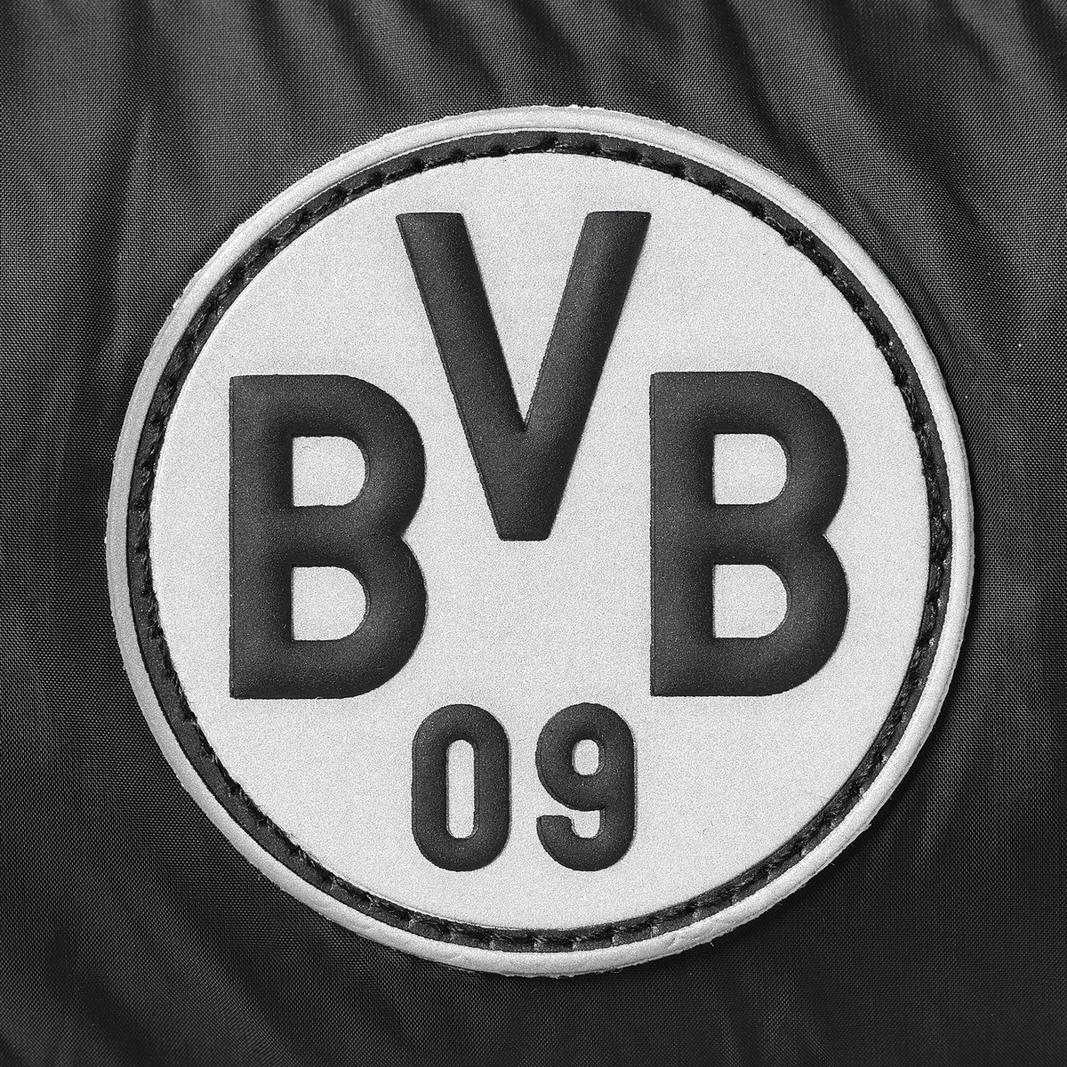Detailansicht des BVB-Logos in schwarzweiß, mit gesticktem Rand und der Aufschrift BVB 09, auf Textiluntergrund.