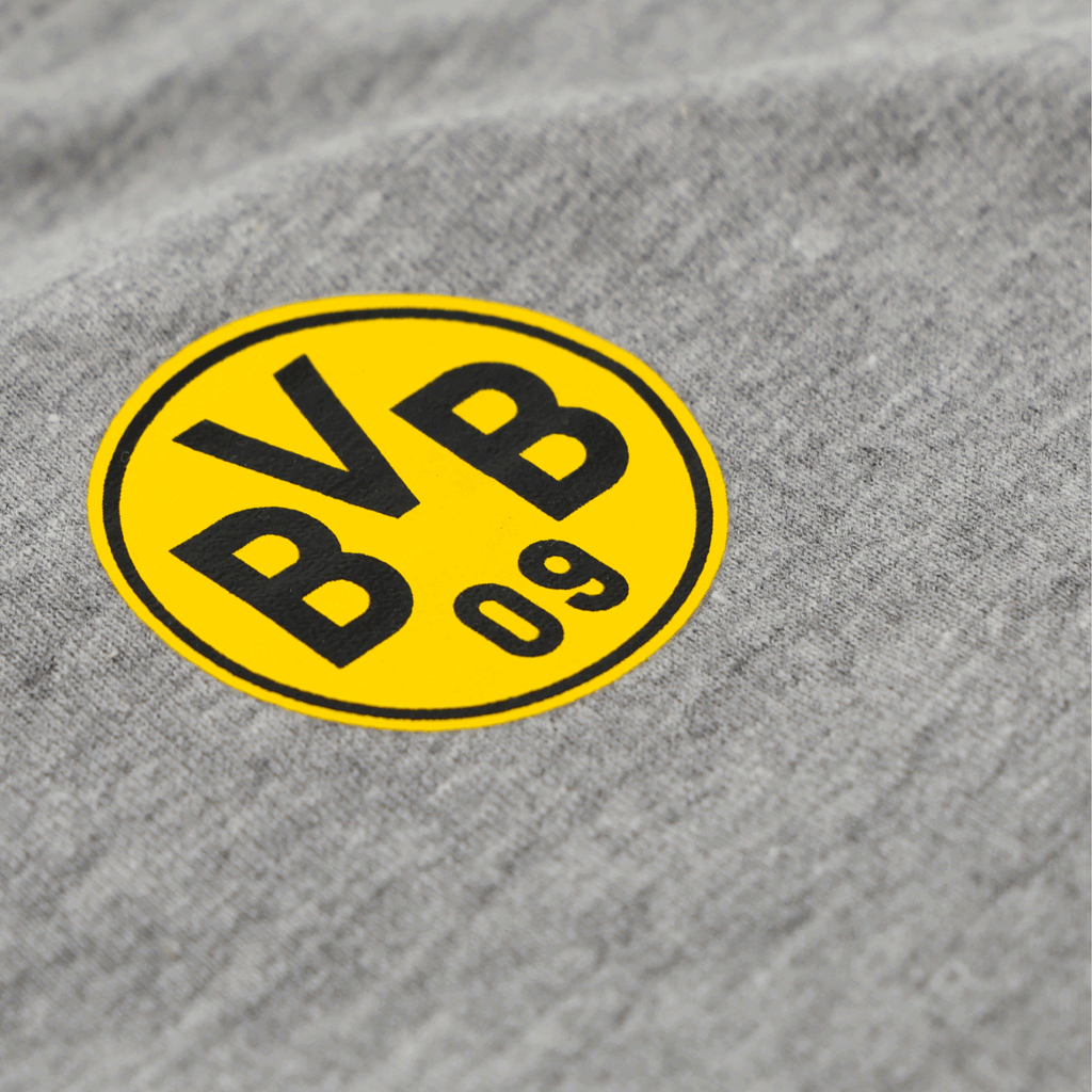 Graues BVB-T-Shirt mit prominentem schwarzgelbem Vereinslogo in Nahaufnahme, ideal für Fans von Borussia Dortmund.