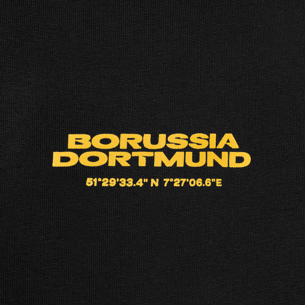 Vista dettagliata dei pantaloni della tuta neri del BVB con la scritta “Borussia Dortmund” in giallo e il motivo a coordinate per bambini.