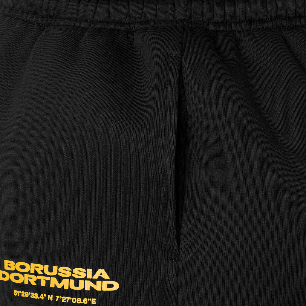 Vista detallada de los pantalones de chándal del BVB para niños, en color negro con el logotipo amarillo del Borussia Dortmund y un diseño cuidado, ideales para los aficionados y para el tiempo libre.