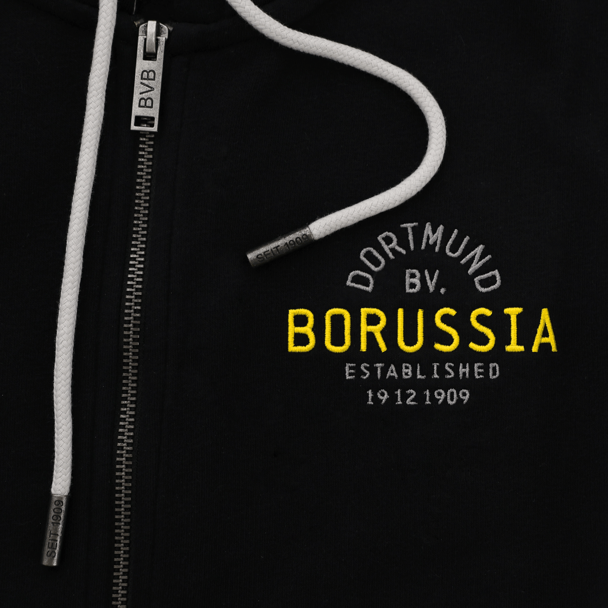 Vista dettagliata della giacca in felpa nera del BVB con cappuccio, scritta "Borussia" in giallo e cordino bianco, ideale per i tifosi del Borussia Dortmund.