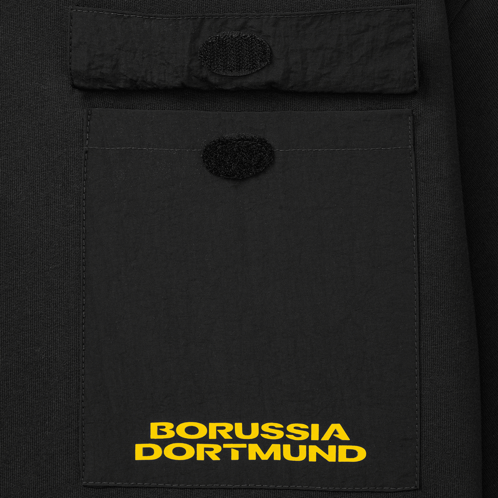 Una camiseta negra del BVB con un práctico bolsillo delantero, decorada con el logotipo amarillo del Borussia Dortmund.