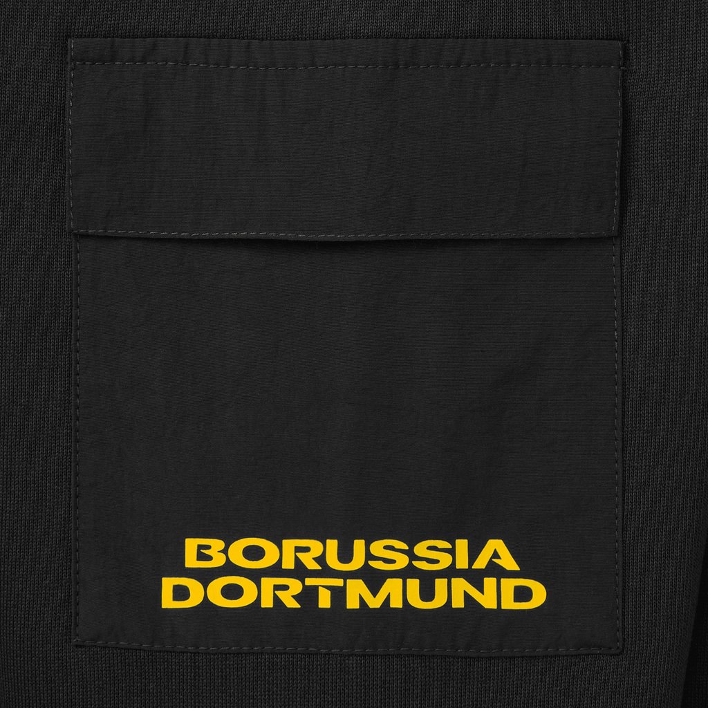 Primo piano di una giacca nera a girocollo con tasca applicata e logo giallo del Borussia Dortmund.