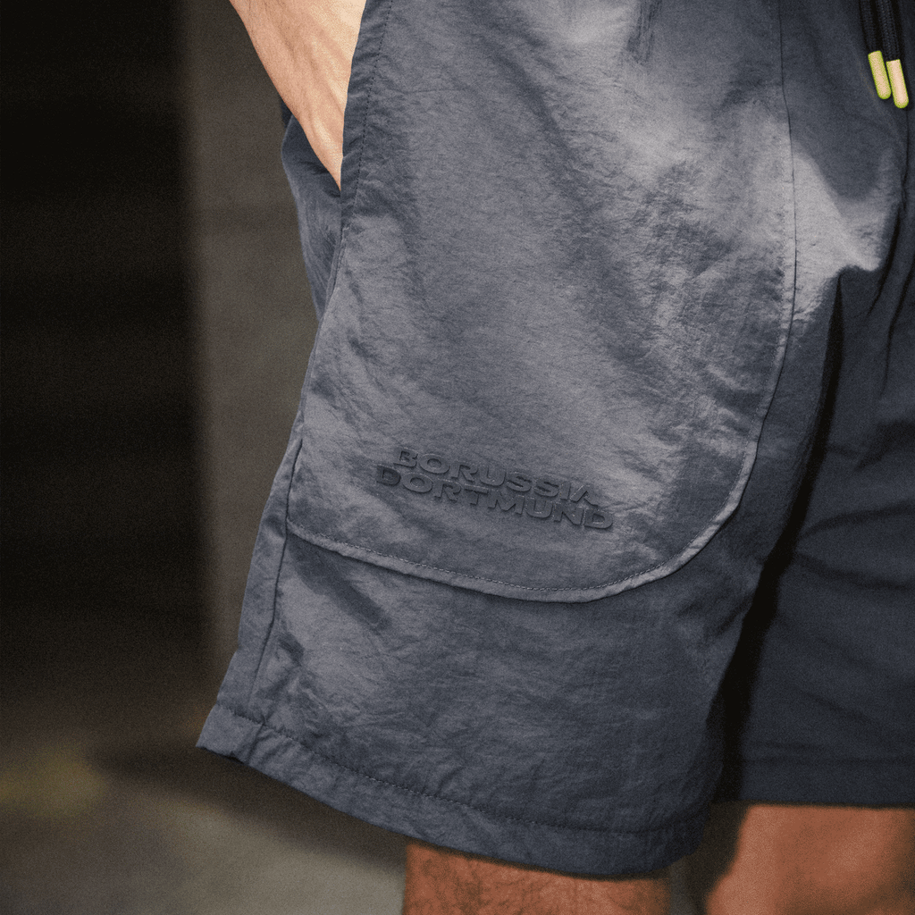 Short bleu foncé du BVB, orné d'un discret logo en relief « Borussia Dortmund » sur la poche latérale, idéal pour le sport et les loisirs.