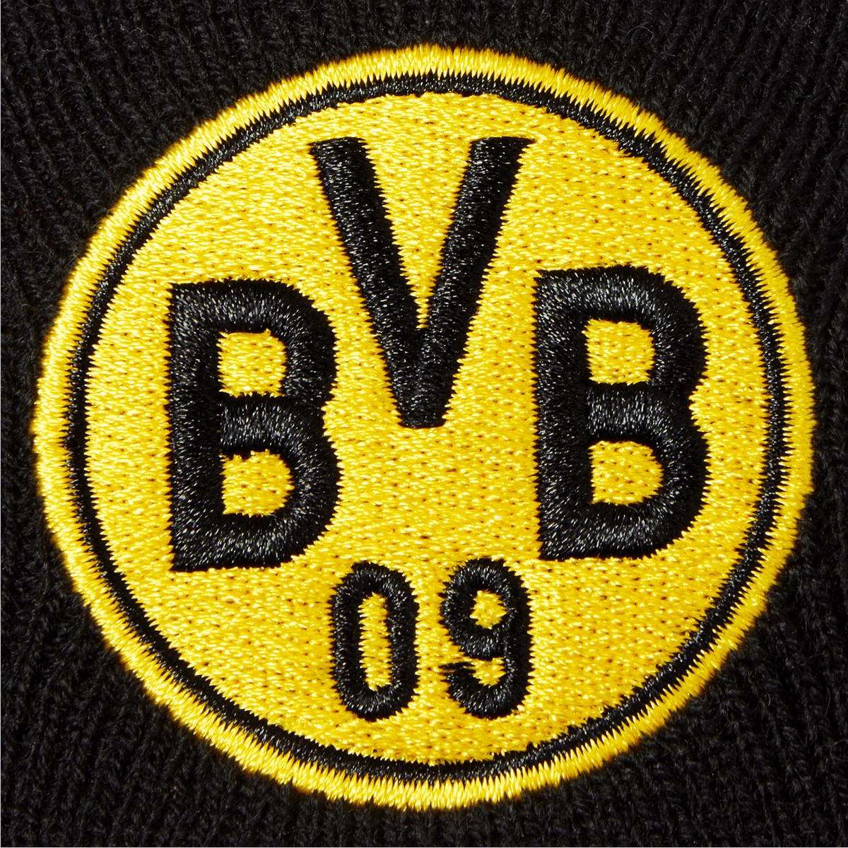 Close-up of a black-and-yellow reversible beanie from Borussia Dortmund featuring a prominent embroidered BVB logo.