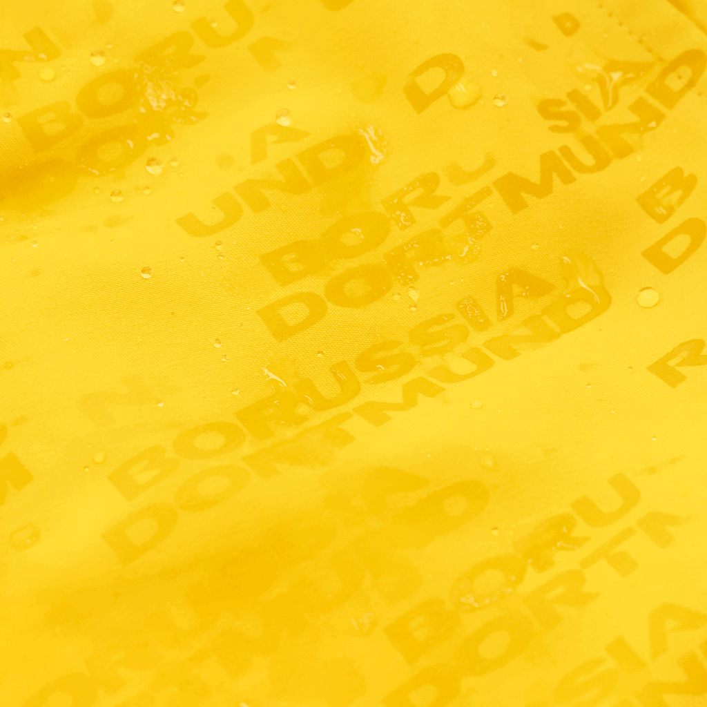 A close-up of yellow swim trunks featuring the Borussia Dortmund logo and a water-repellent finish.