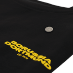 A matte silver BVB pin emblem on black fabric with yellow "Borussia Dortmund" lettering.
