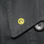 エンブレムと「BVB 09」の文字が入った黄色いBVBピン。黒い布の上に写っています。ボルシア・ドルトムントのファンにぴったりです。