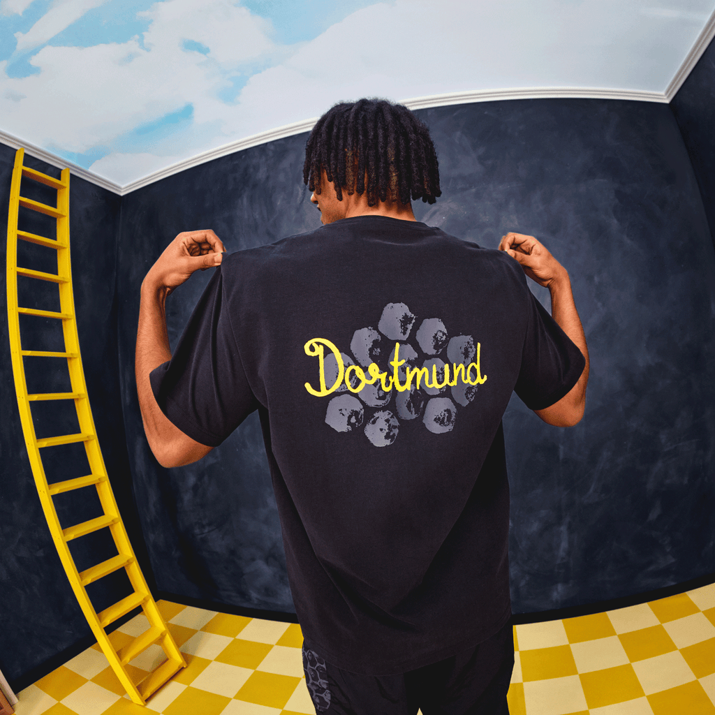 Black BVB KidSuper Graphic T-shirt for men, featuring yellow "Dortmund" lettering and a graphic print on the back.
