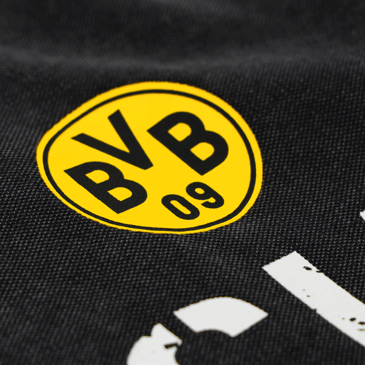 图片展示的是印在黑色面料上的多特蒙德（BVB）队徽特写，该队徽出自BVB Elements系列的一款Polo衫。