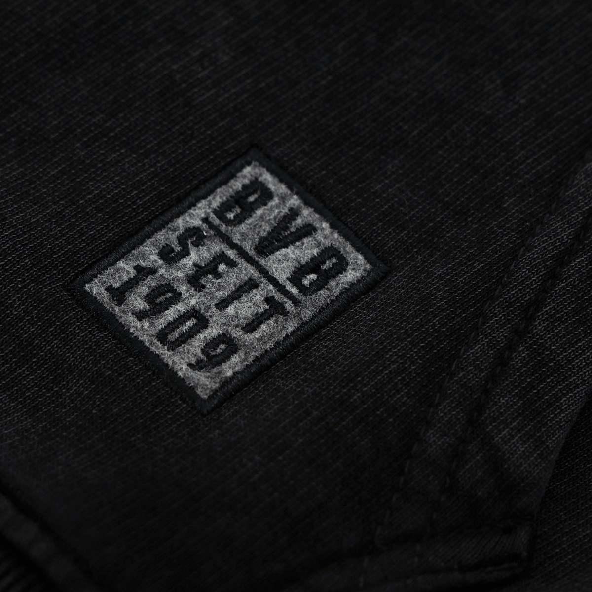 Detailaufnahme des BVB Elements Hoodies in Schwarz mit grauem BVB-Logo und 1909-Schriftzug; ideal für Fans von Borussia Dortmund.