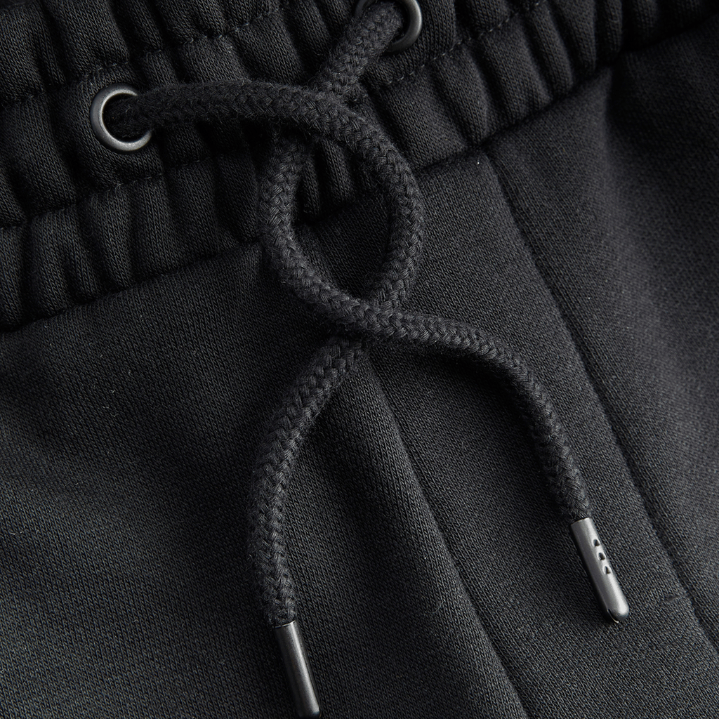 Vista detallada de los pantalones de chándal negros «BVB Essentials» con cordón, un artículo de alta calidad para los aficionados del Borussia Dortmund.